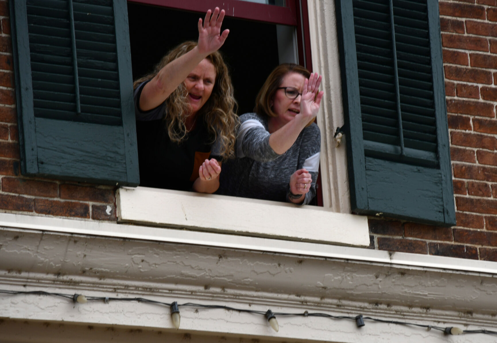 Spectators lean out a window to wave